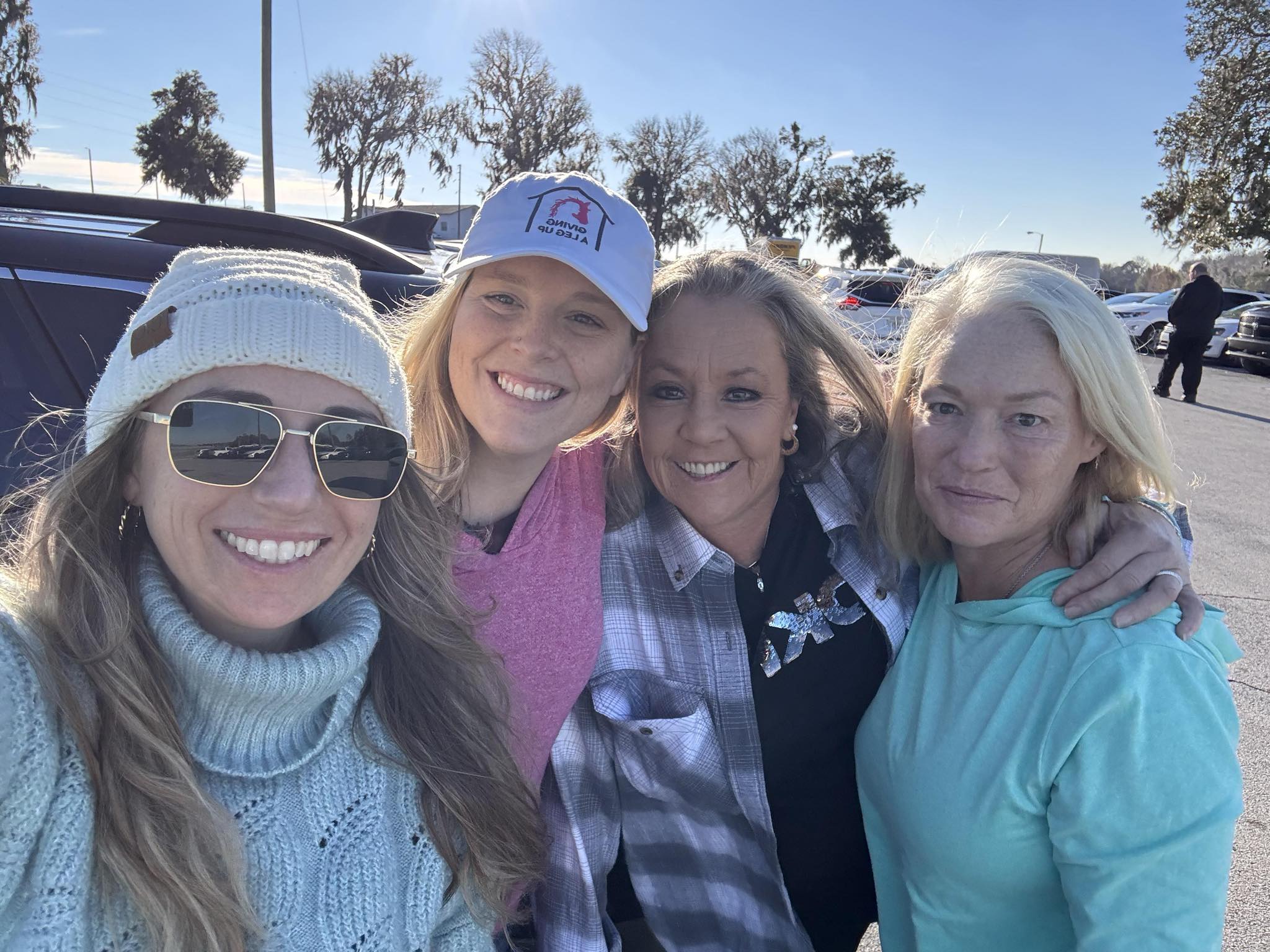 four women taking a photo together outside
